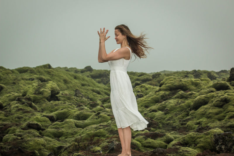 Woman standing on a hill side with prayer hands